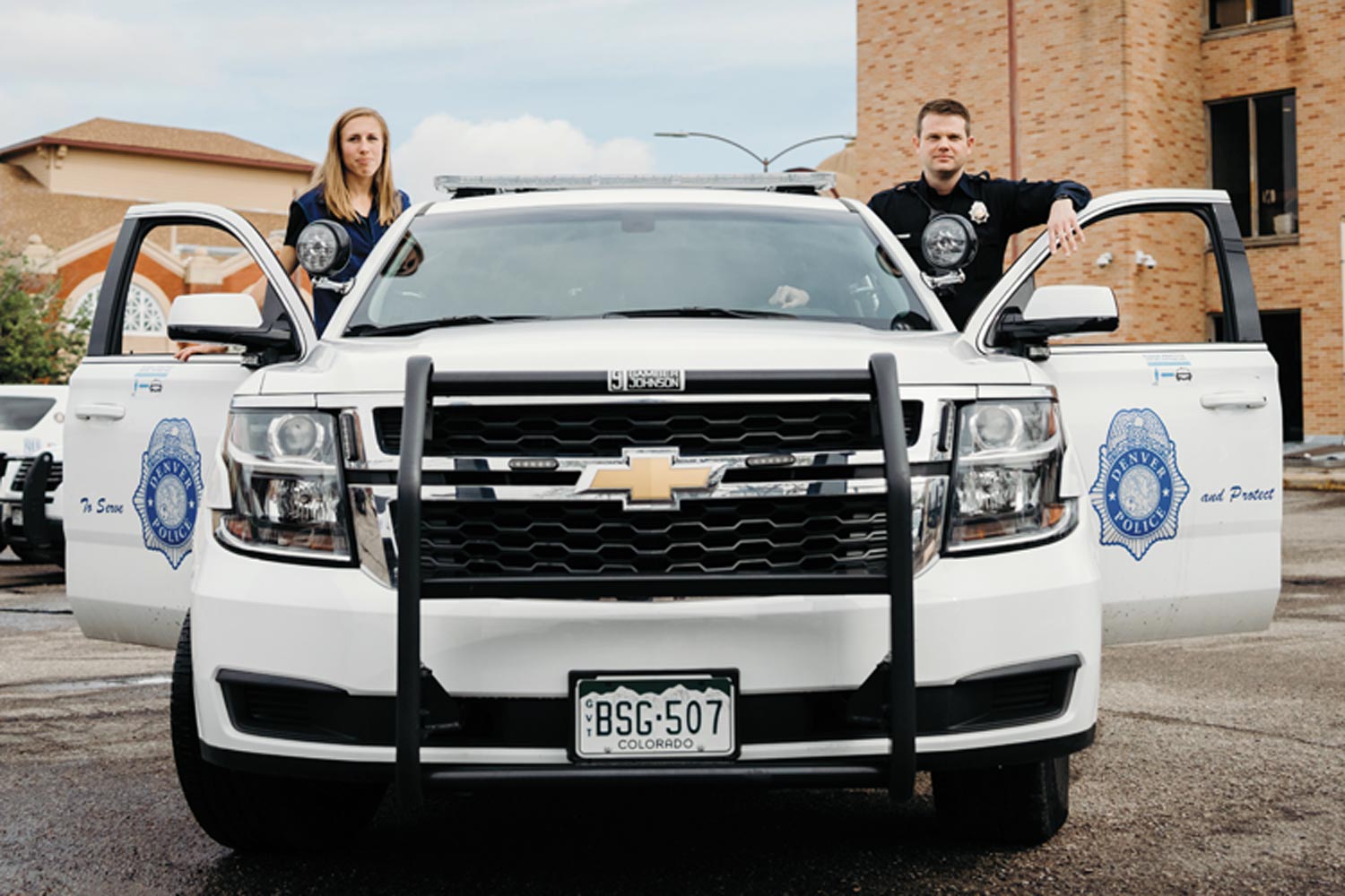 Image of Kathy Evans ’14 and a police officer standing by a patrol car