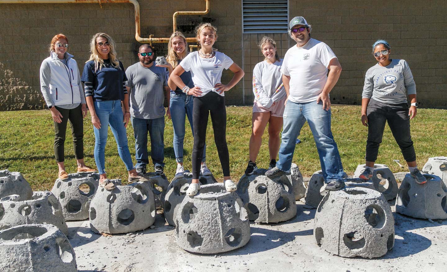 Photo of students standing atop concrete reef balls